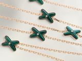 six croix en émail vert suspendues à des chaînes en or et ornées de diamants