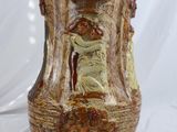 un vase marron orné d'un visage sur fond blanc