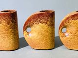 trois vases bruns percés de trous, posés sur une table