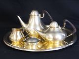 a silver tea set on a silver tray on a black background