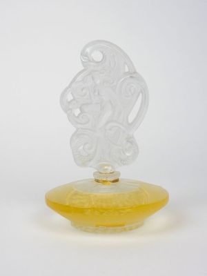 une image représentant un vase en verre jaune orné d'un visage sculpté