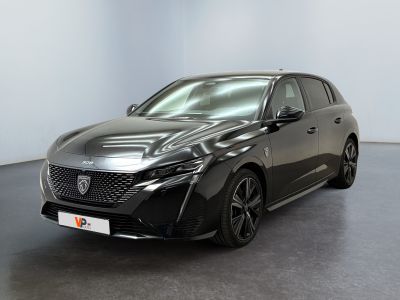 Une voiture noire est garée dans une pièce aux murs blancs.