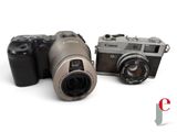two cameras sitting next to each other on a white surface