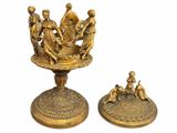brass figurines of a group of people sitting on a pedestal