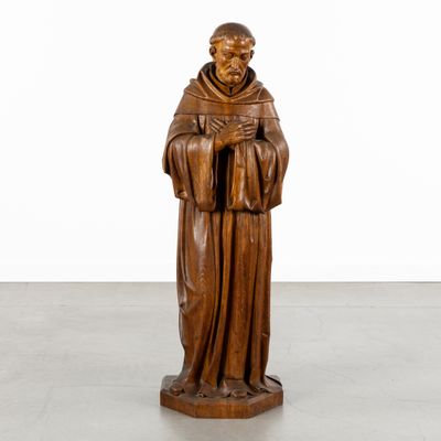 a wooden statue of a monk holding a book