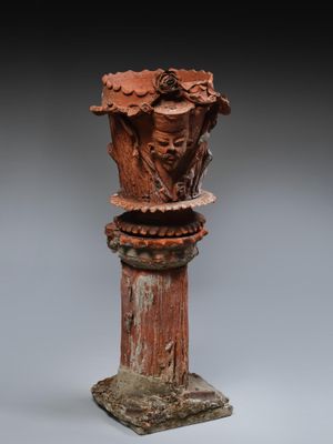 une image représentant un vase rouge surmonté d'un visage