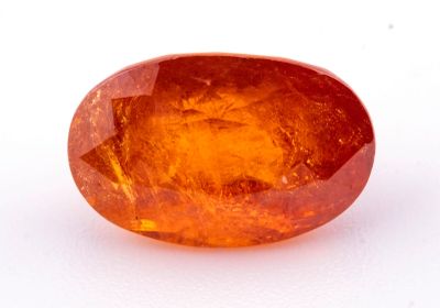 un gros plan d'un saphir orange de forme ovale posé sur une surface blanche