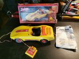 une petite voiture jaune posée sur une table, à côté d'une boîte de jouets