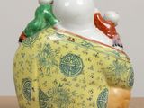 a ceramic figurine of a man with two birds on his back