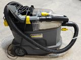 un aspirateur posé par terre, muni d'un tuyau