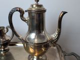 a silver tea pot sitting on a silver tray on a table