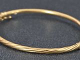 gros plan d'un bracelet en or sur une surface noire