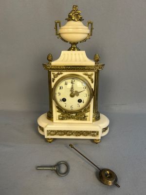 une petite horloge blanche ornée d'un motif doré