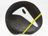 une assiette noire ornée d'un motif blanc et jaune