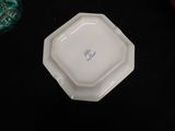 a white plate with a blue flower on it on a table