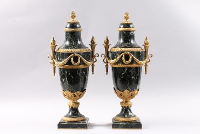paire de vases noirs et dorés munis d'anses, posés sur des socles en marbre