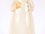 une figurine blanche représentant une femme coiffée d'un chapeau
