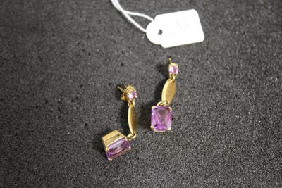 paire de boucles d'oreilles ornées d'améthyste et de pierres roses sur un fond noir