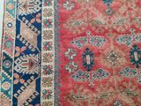 an old rug with a red and blue border on a white floor