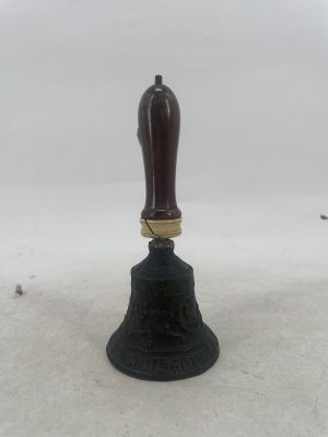 une cloche munie d'une poignée en bois, posée sur un sol recouvert de neige