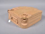 une valise beige munie d'une étiquette, posée sur une surface grise