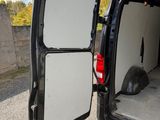 une camionnette blanche dont la porte est ouverte, garée sur le bord de la route