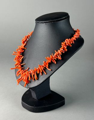 a close up of an orange necklace on a black mannequin