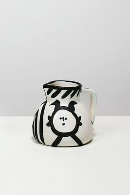 un vase noir et blanc sur lequel est peint un visage
