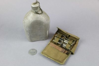 a small white bottle with a metal latch next to a coin