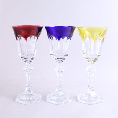 trois verres à vin de couleurs différentes posés les uns à côté des autres sur une surface blanche