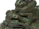 a statue of a frog that is laying on a leaf