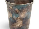 a metal cup that is sitting on a white surface