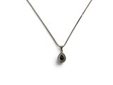 un collier en argent orné d'une pierre noire en forme de larme, monté sur une chaîne