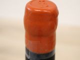 a close up view of a red wine bottle with a black cap