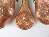 three copper spoons hanging on a wall next to each other