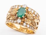 a close up of a gold ring with a green stone surrounded by diamonds