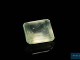 une pierre de quartz verte posée sur une surface noire, avec un fond noir