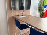 tables and chairs in a meeting room with a flat screen tv