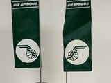 deux drapeaux verts et blancs fixés sur un support posé sur une surface blanche