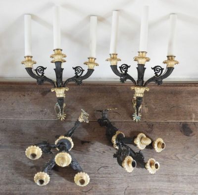 two black and gold candelabs with white candles on top of a wooden table