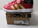 Les baskets Adidas rouges et dorées sont posées sur une boîte en carton