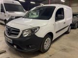 La camionnette blanche est garée dans le garage, à côté d'autres véhicules.