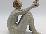 sculpture of a woman sitting on her knees holding a bird