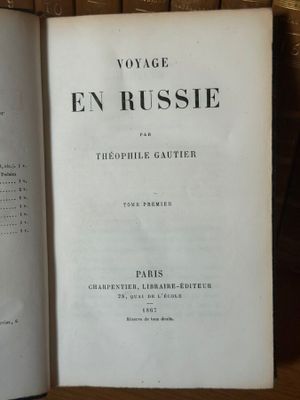 un livre ouvert posé sur une table en bois, à côté d'une pile de livres