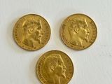three gold sovereigns, one of which has a head of a man and one of which is a woman