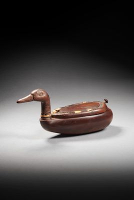 an old wooden duck shaped object sitting on top of a table