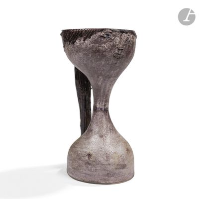 un vase gris posé sur une surface blanche