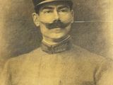 une vieille photo d'un homme en uniforme, portant une moustache