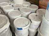 many buckets of white paint sitting on a pallet