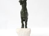 statue of a goat standing on a rock on a white surface